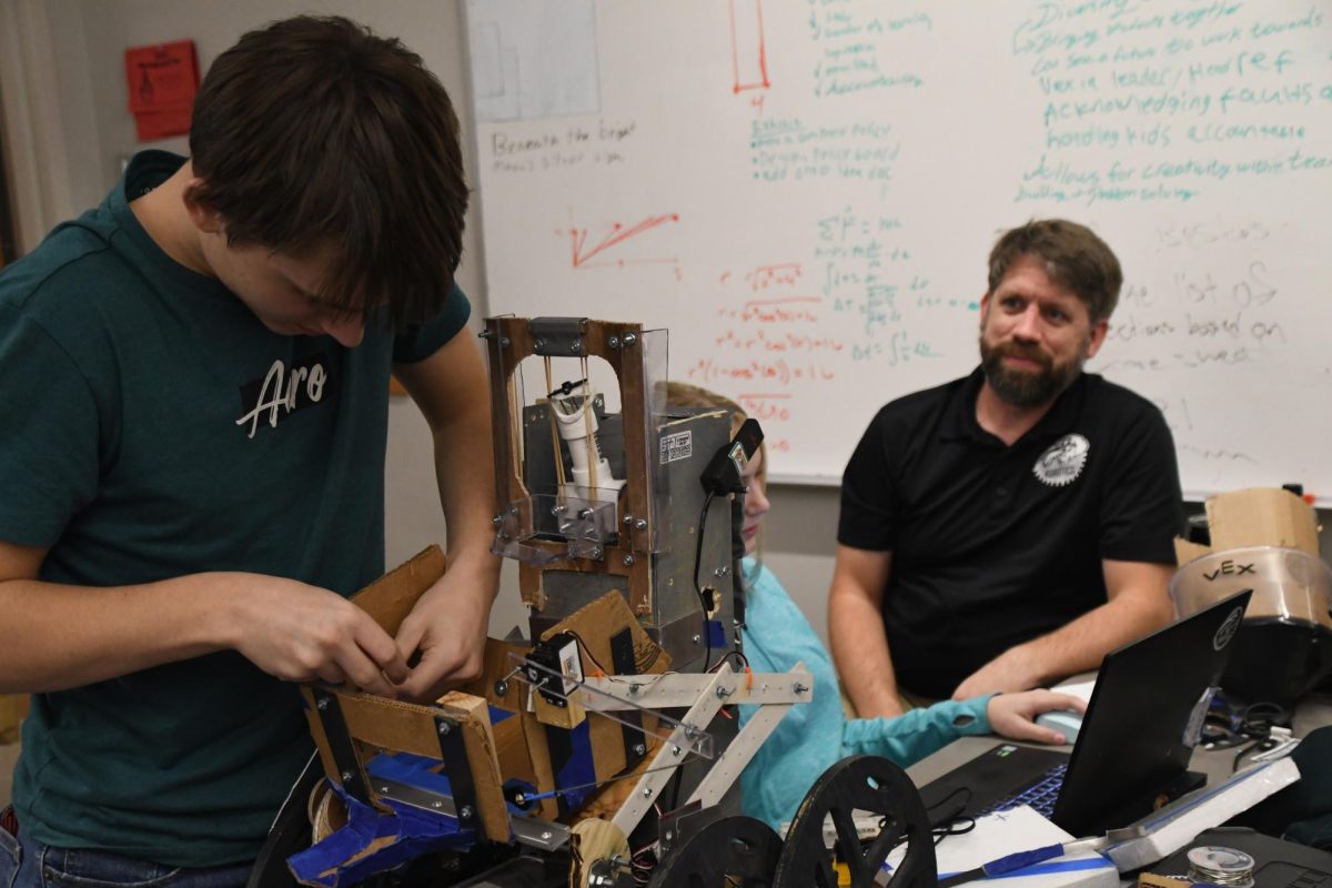Tyler Richters (11) Abigail Wise (11) and Scott Glass work on adjustments to their robot in preparation for the Midwest robotics regionals. The tournament will over on Dec. 6-7 in Wichita, Kan.