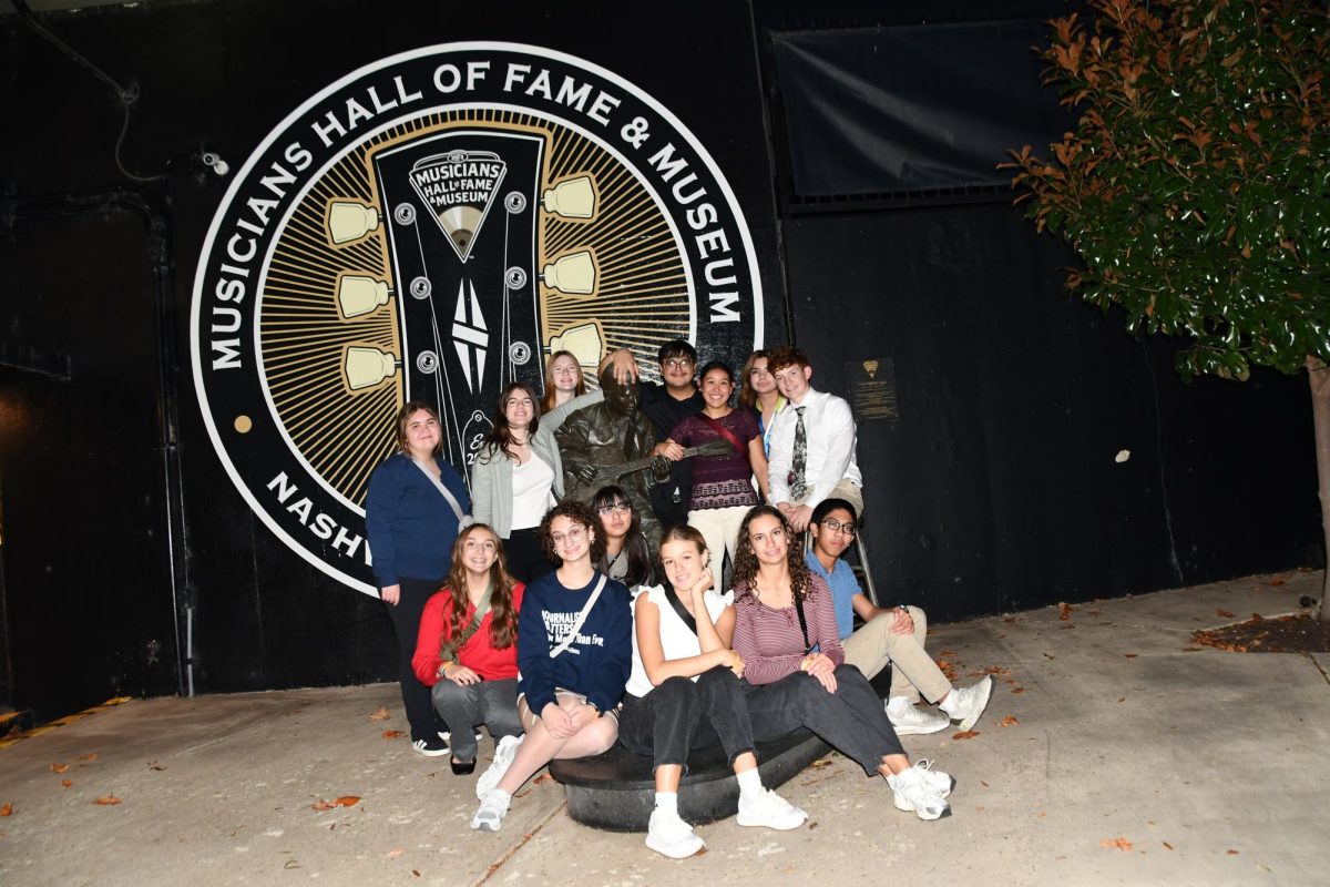 Brooklyn Chapman (11), Stefanie Eder (11), Ali Gigot (11), Kevin Jaco (11), Savanna Reyes (11), Kailee Uribe (11), Isaac Owens (11), Olivia Dunlap (11), Isa Saddler (11), Ailyn Robledo (11), Karly James (11), Megan Burr (11), and Steve Marilou (11) sit outside Musicians Hall of Fame and Museum during the nightlife of Nashville, Tennessee.