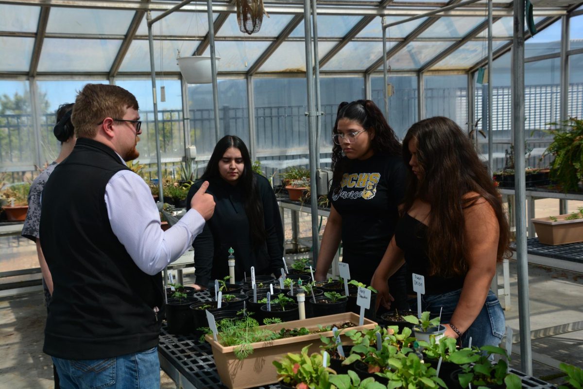 Cade Anderson, Plant & Soil Science teacher, speaks to Nairoby Sanchez-Franco (10) and Maribel Hernandez (11) about the plants housed in the green house. The Introduction to Agriculture class meets once a week in the green house to learn about and care for the plants.