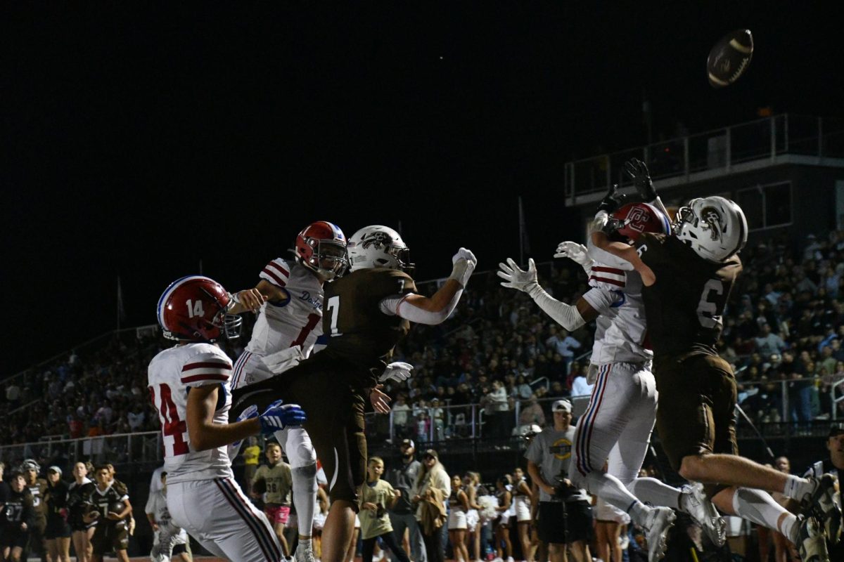 Jhett Price (12) and Drew Strecker (11) leap up to defend Red Demons pass during the Hatchet game on Oct. 17. The Buffalos lost 14-20.