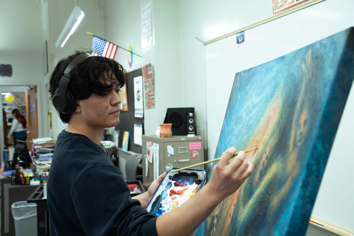 Cesar Morales (12) adds the final touches to his painting on Oct. 9. He is easily found in the art hall in the basement of Arts & Comm.