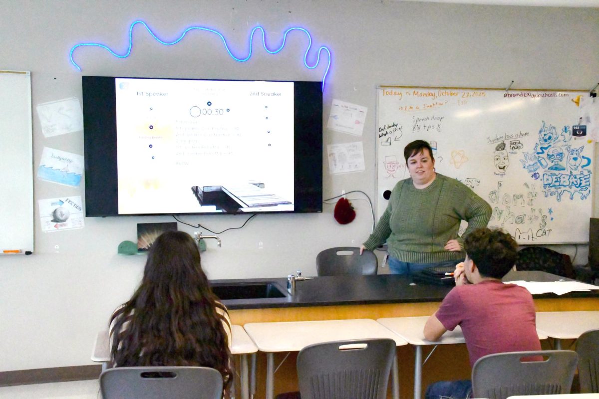 Marisela Loza (11) and Luis Visco (11) watch as Aimee Brandt explains the activity for the advanced debate class. The projector was replaced with a TV first semester of the 2024-2025 school year.